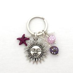 a keychain with two charms attached to it's sides and a sun face on the front