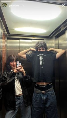 two people standing in an elevator with their arms around each other and one person taking a selfie