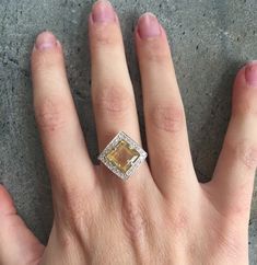 a woman's hand with a yellow diamond ring on top of her left hand