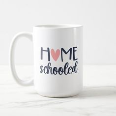 a white coffee mug with the words home schooled on it and a red heart