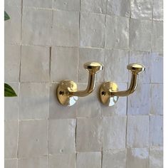 two brass - plated sconces hang on a white tiled wall in the bathroom