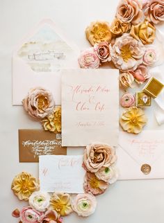 the wedding stationery is laid out on top of each other, including pink and gold flowers