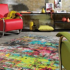 a living room area with colorful rugs and modern furniture on the floor in front of a brick wall