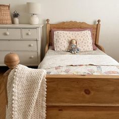 a bed with a teddy bear sitting on top of it next to a night stand