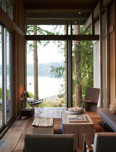 a living room filled with furniture and lots of windows next to a tree covered hillside