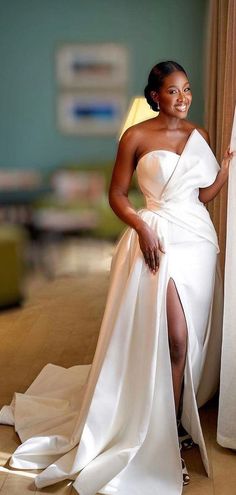 a woman in a white dress leaning against a curtain