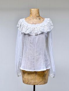 "* Gunnies peasant blouse c 1970s * Ivory cotton crinkle gauze * Elasticized neckline features 4\" wide ruffled lace collar - can be worn on or off shoulders * Long, full raglan sleeves are elasticized at wrist with narrow lace trim  * Squared hem Label: Gunnies by Jessica San Francisco Excellent condition Bust: 36 Waist: 28 Shoulder:15 Sleeve: 24 Length: 21 Please view my Shop Policies here prior to placing an order as all sales are final: http://www.etsy.com/shop/ranchqueenvintage/policy ❤ Not Bohemian Linen Blouse With Ruffles, Bohemian Blouse With Ruffles For Gatherings, White Boho Collar Peasant Top, White Peasant Top With Boho Collar, White Cotton Cottagecore Peasant Top, Cottagecore White Cotton Peasant Top, Cream Bohemian Peasant Top For Daywear, Cotton Ruffle Blouse For Gatherings, Peasant Tops With Ruffles For Gatherings