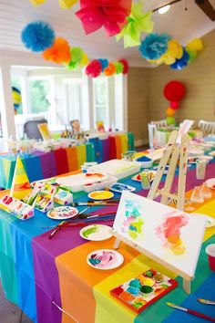 a colorful party with paper decorations and paintings on the table, including tissue pom poms