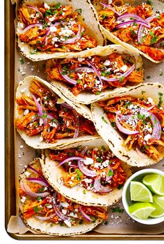 chicken tacos with red onions, cilantro and limes on a baking sheet