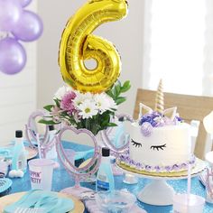 a blue table topped with a cake and balloons