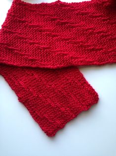 a red knitted scarf laying on top of a white table