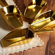 gold colored dishes are sitting on a white napkin next to a brown wooden tablecloth