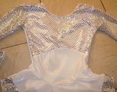 a white bodysuit with sequins on it sitting on the ground next to a tile floor