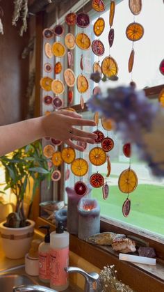 a person reaching for some orange slices on a window sill in front of a kitchen sink