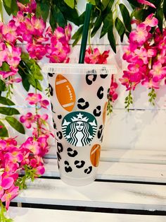 the starbucks cup is decorated with football and leopard print, along with pink orchids