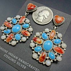 "NAVAJO MULTI-STONE CLUSTER EARRINGS These joyful earrings features clustered cabs of clear blue turquoise, orange spiny oyster shell, and white mother of pearl. Clustered conchos dangle from orange spiny oyster shell heart posts. These earrings will be a cherished addition to your collection of quality Native American jewelry. MEASUREMENTS: Earrings measure 2 1/8\" x 1 1/4\" WEIGHT: 24.0 grams SIGNED: W (Navajo) STERLING: yes, stamped STERLING" Blue Multi-stone Earrings For Jewelry Making, Jewelry Measurements, Shell Heart, Orange And Turquoise, Spiny Oyster, Oyster Shell, Coral Turquoise, Cluster Earrings, American Jewelry