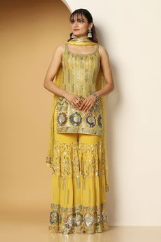 Yellow sleeveless padded short kurta in georgette base with metallic sequin vines, chevron and floral swirl embroideries. Paired with a sequin garden embellished tiered sharara and ditsy sequin motif embellished net dupatta. - Aza Fashions Yellow Sharara, Embroidered Sharara, Kurta Sharara Set, Kurta Sharara, Short Kurta, Sharara Set, Net Dupatta, Indian Fashion Designers, Pernia Pop Up Shop