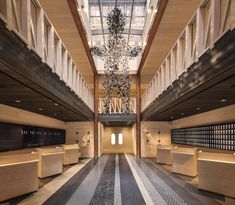 an empty lobby with benches and chandelier in the center, surrounded by large windows