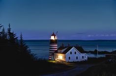 the lighthouse is lit up at night by the water