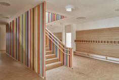 an empty room with multicolored striped wallpaper and wooden stair case in the center