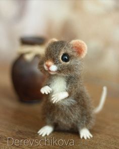 a tiny mouse sitting on top of a wooden table