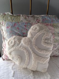 two decorative pillows sitting on top of a bed next to an ironing board headboard