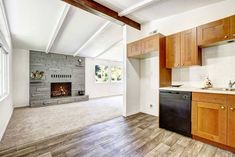 an empty kitchen and living room with wood flooring in the house, including a fireplace