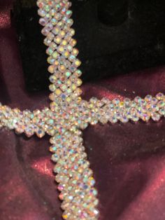 a cross made out of beads sitting on top of a purple cloth