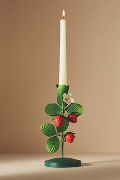 a candle that is sitting on top of a table with strawberries and leaves in it