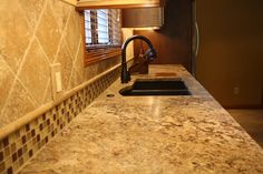 a kitchen with marble counter tops and tile backsplash, along with a black faucet