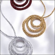 three different colored necklaces sitting next to each other on a white surface and one is gold, silver, and red