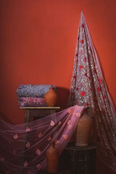 a red wall and some vases on a table with a purple net over it