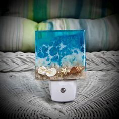 a blue and white glass block sitting on top of a bed covered in sea shells