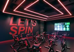 there is a gym with spinning bikes in the room and a large screen on the wall