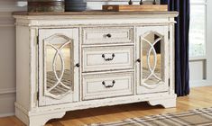 an antique white cabinet with mirrored doors and drawers