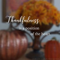 a vase filled with yellow flowers sitting on top of a table next to two pumpkins