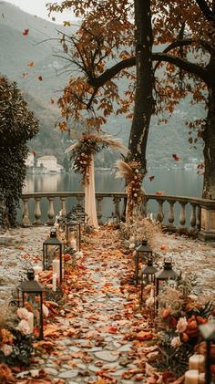 an outdoor wedding setup with candles and flowers on the ground, surrounded by trees in fall colors