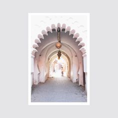 an archway leading into a white building with arches and lights hanging from it's sides