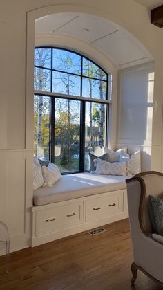 a window seat with pillows on it in front of a large window