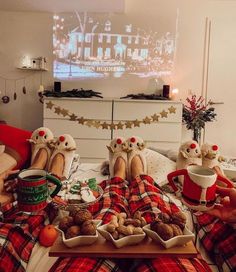 two people sitting on a couch with food in front of them and a tv screen behind them