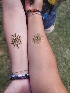 two girls with matching tattoos on their arms holding each other's hands in the grass