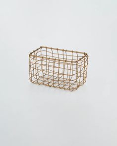 a gold wire basket sitting on top of a white surface with no one in it