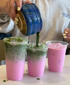 three cups with different colored drinks being poured into them