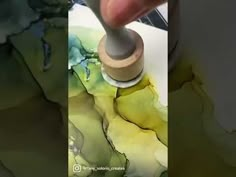 a person is using a paint brush to create an abstract painting on paper with watercolors