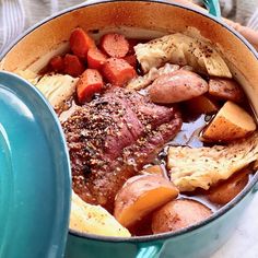 a pot filled with meat and vegetables on top of a table next to a person