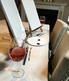 a glass of wine sitting on top of a table next to a painting easel