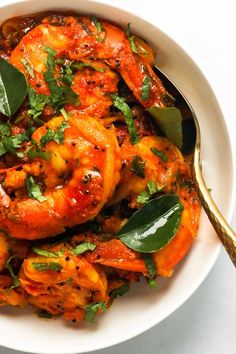 a white bowl filled with cooked shrimp and garnished with herbs