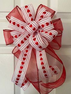 a red and white bow with hearts hanging on the front door ornament for valentine's day