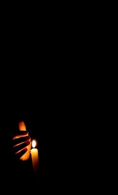 a person holding a lit candle in the dark