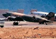 an airplane is parked on the runway in front of several other planes and trucks behind it